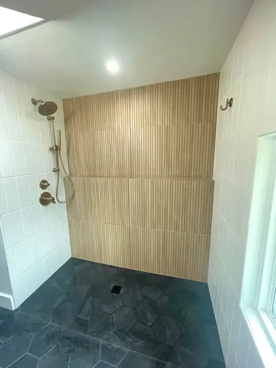 Empty tiled shower with beige wood-look accent wall and dark floor drain
