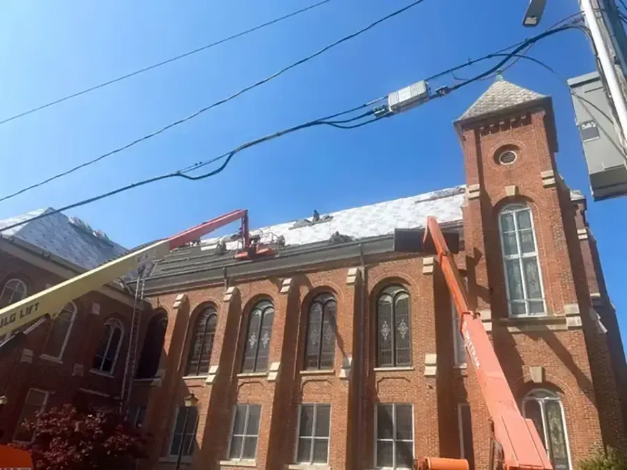 Brick church facade with snow on the roof and a tall tower under a clear blue sky