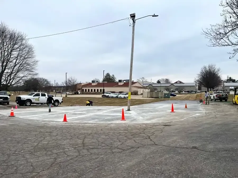 Parking lot with orange cones around a snowy roundabout and a utility pole in the center