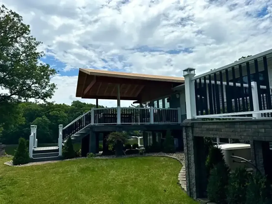 Raised deck and covered patio overlooking a grassy yard under a cloudy sky