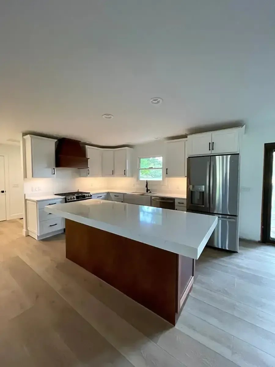 Bright modern kitchen with white island, stainless steel appliances, and wood flooring