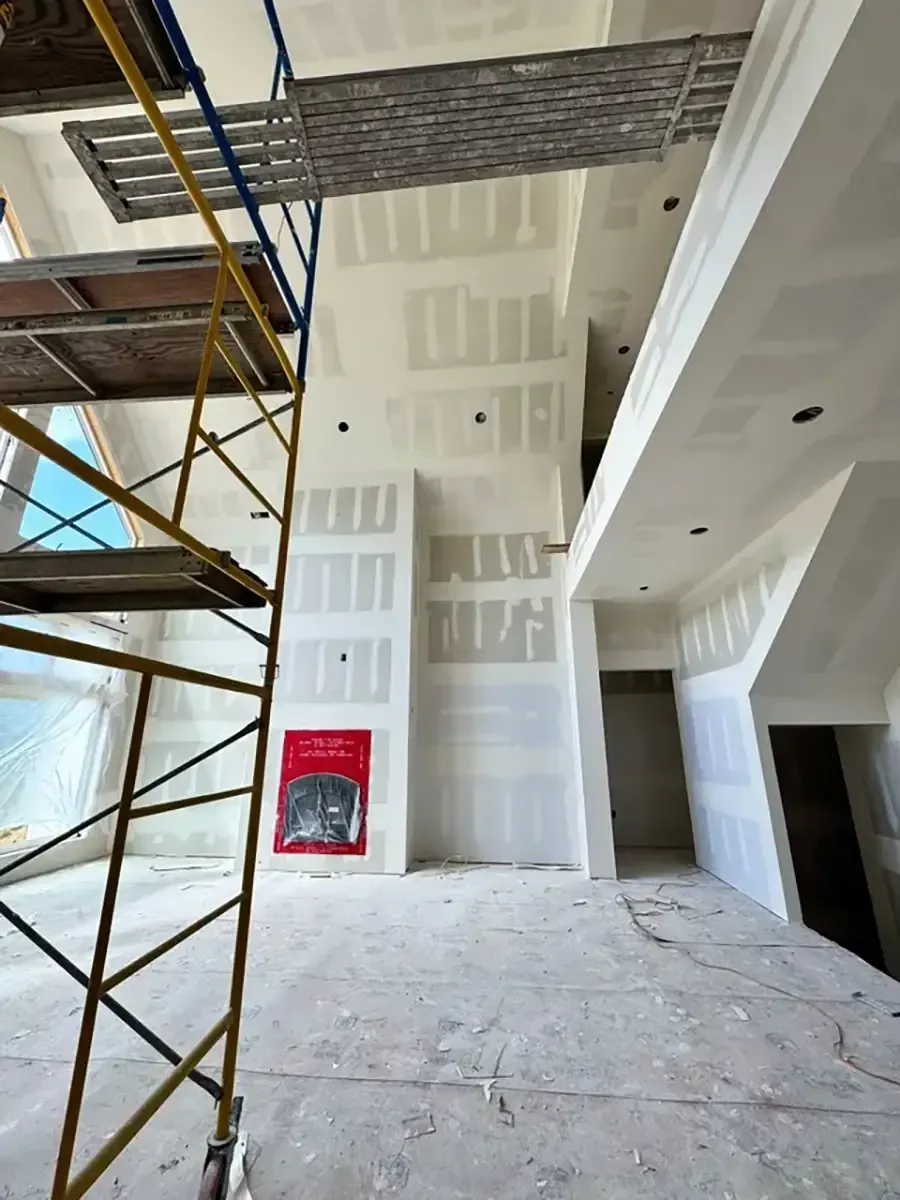 Interior construction site with scaffolding, drywall, unfinished walls, and a red fire extinguisher cabinet.
