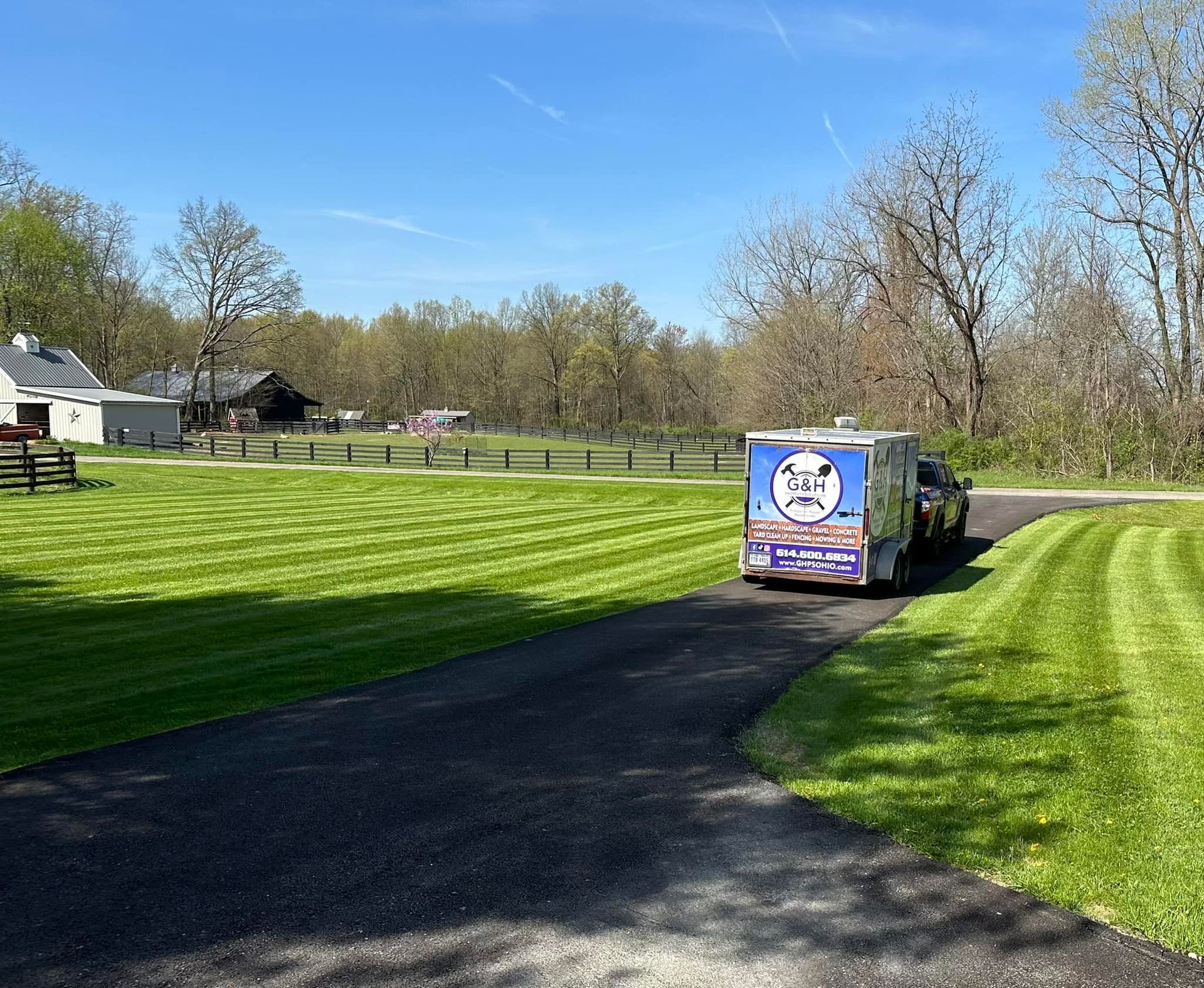 A truck is parked on the side of a road next to a lush green field.