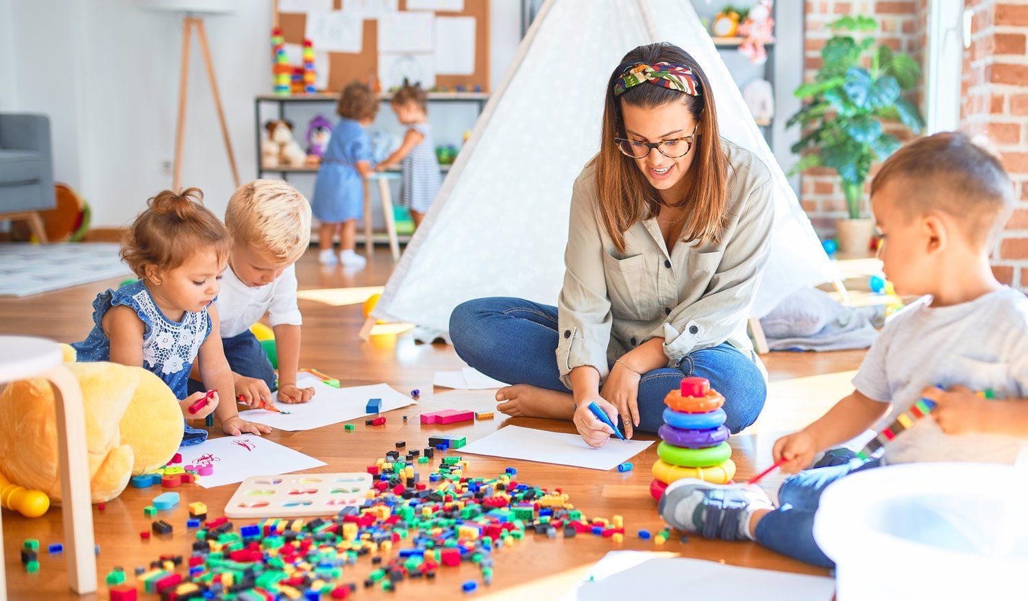 A woman is sitting on the floor playing with children.