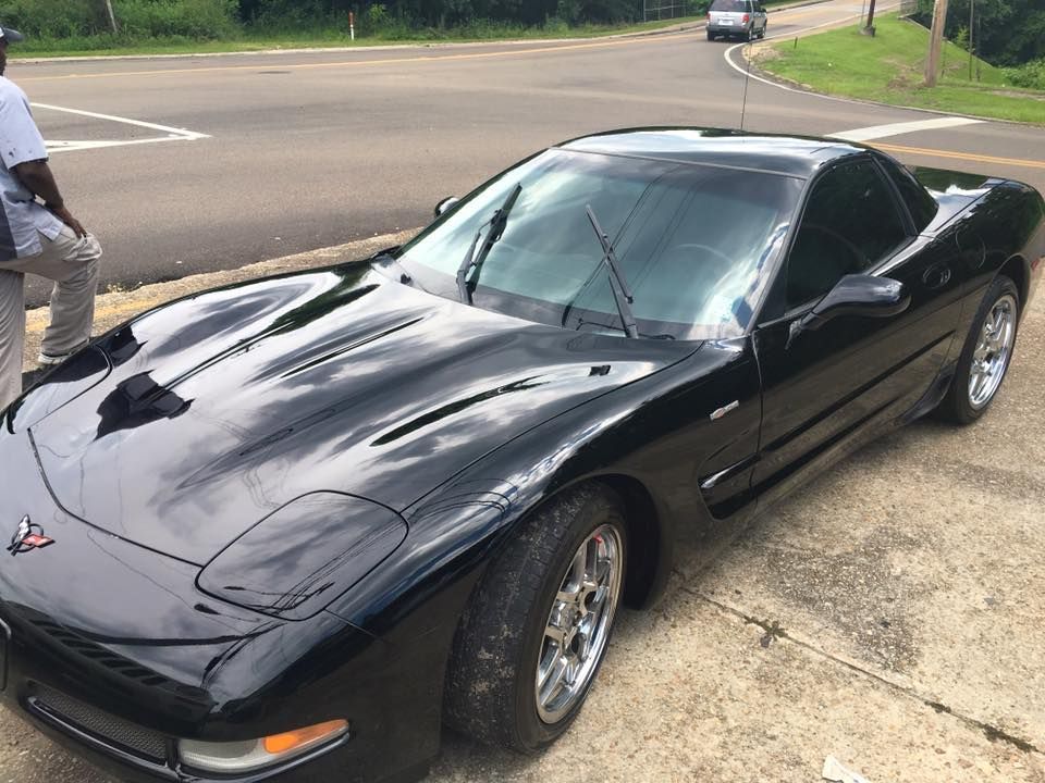 A black corvette is parked on the side of the road.