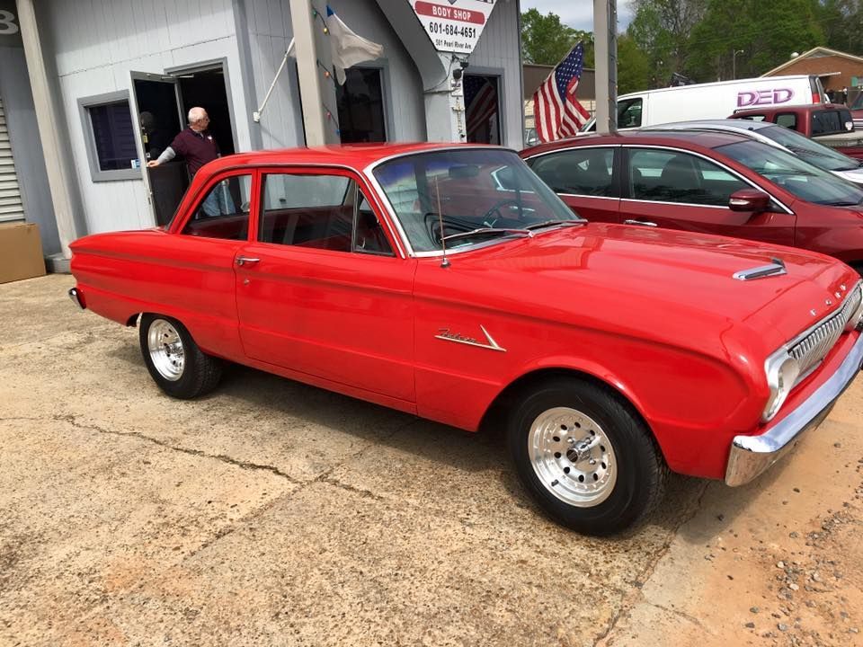 A red car is parked in front of a car dealership.