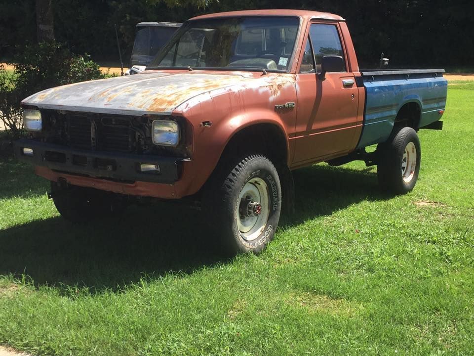 An old rusty pickup truck is parked in the grass.
