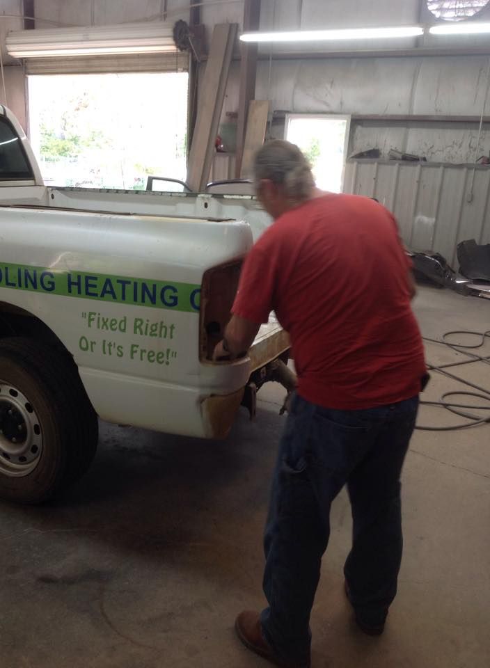 A man in a red shirt is working on a heating company truck.