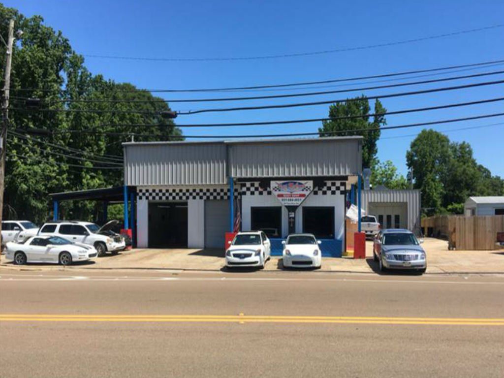 A row of cars are parked in front of a car dealership