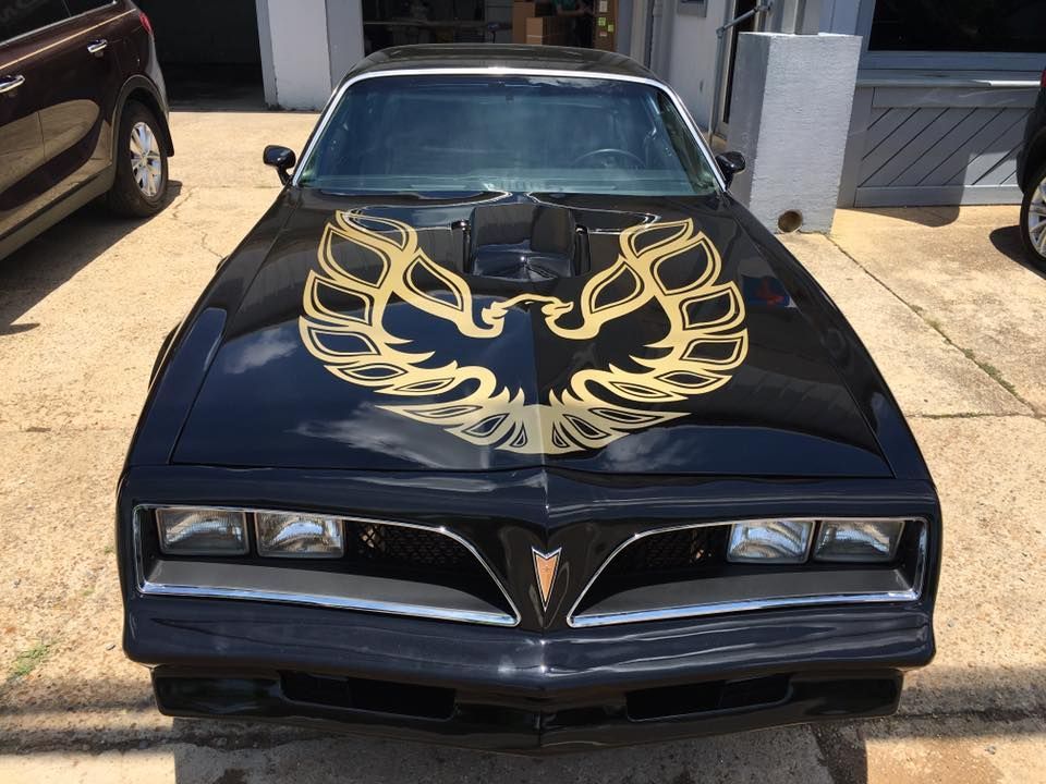 A black pontiac trans am with a gold eagle on the hood