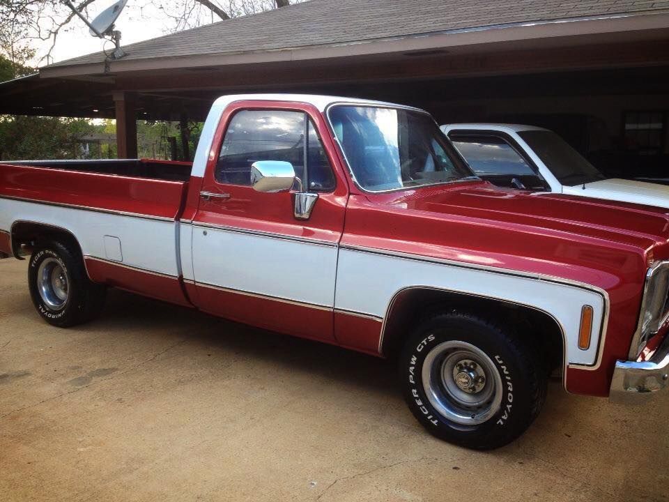 A red and white truck is parked in front of a garage