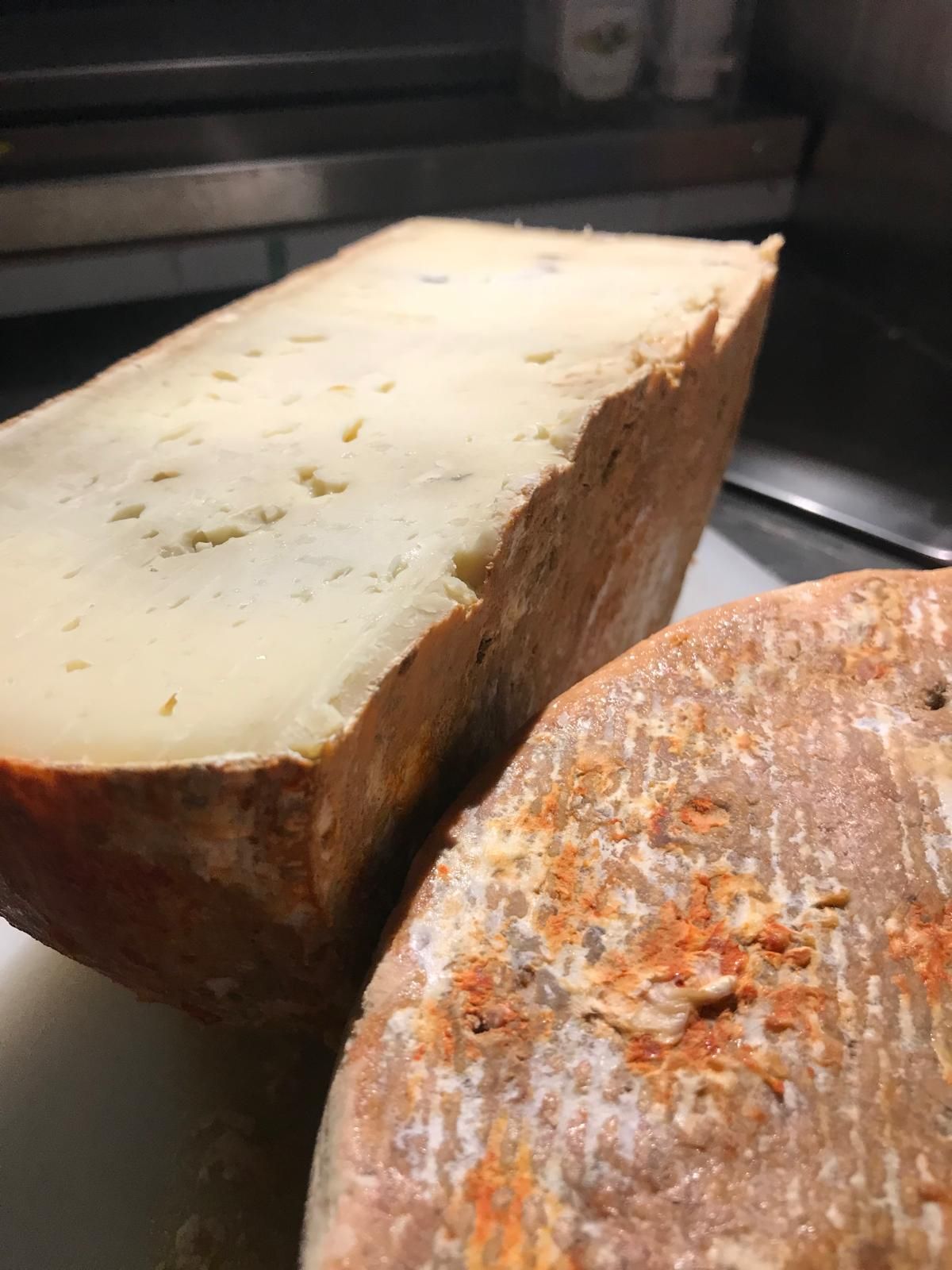 Due spicchi di formaggio, uno chiaro e uno con la crosta arancione, su un bancone della cucina.