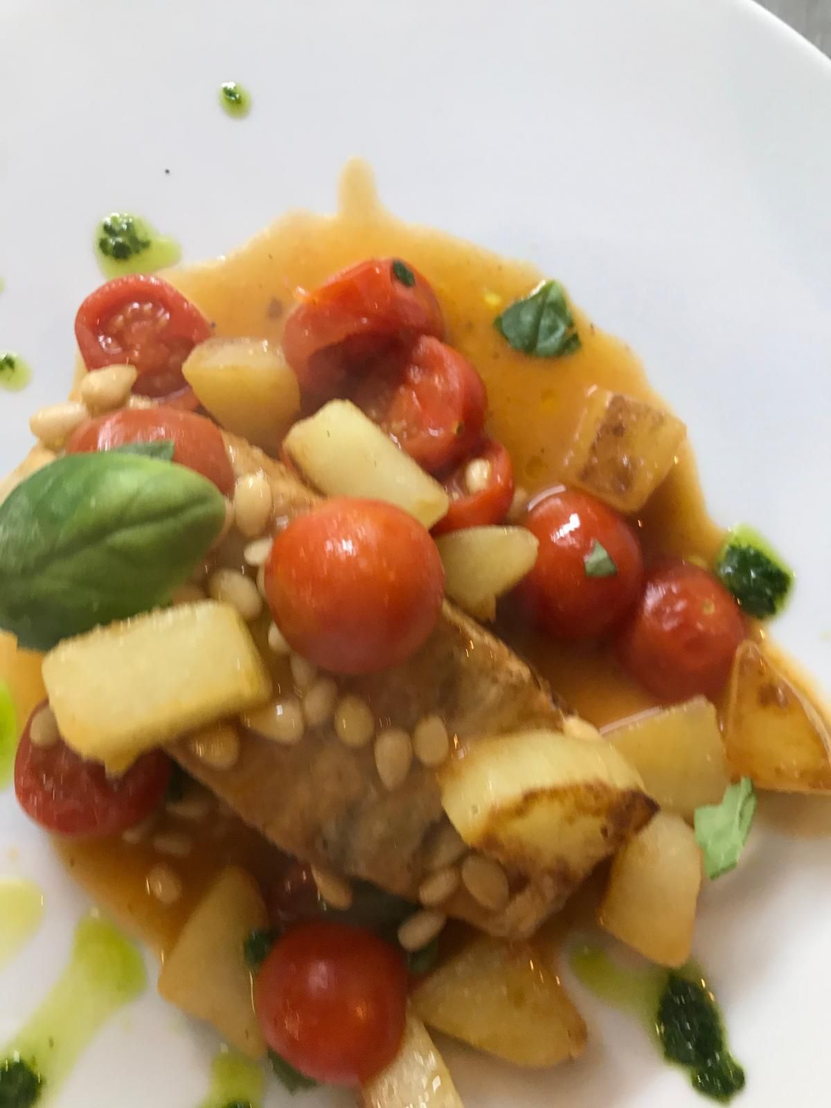 Insalata di pomodori e pane con foglie di basilico e un filo di salsa verde.