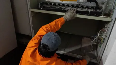 Empleado de una tienda le muestra un disco de freno a un cliente en una tienda de repuestos para automóviles.