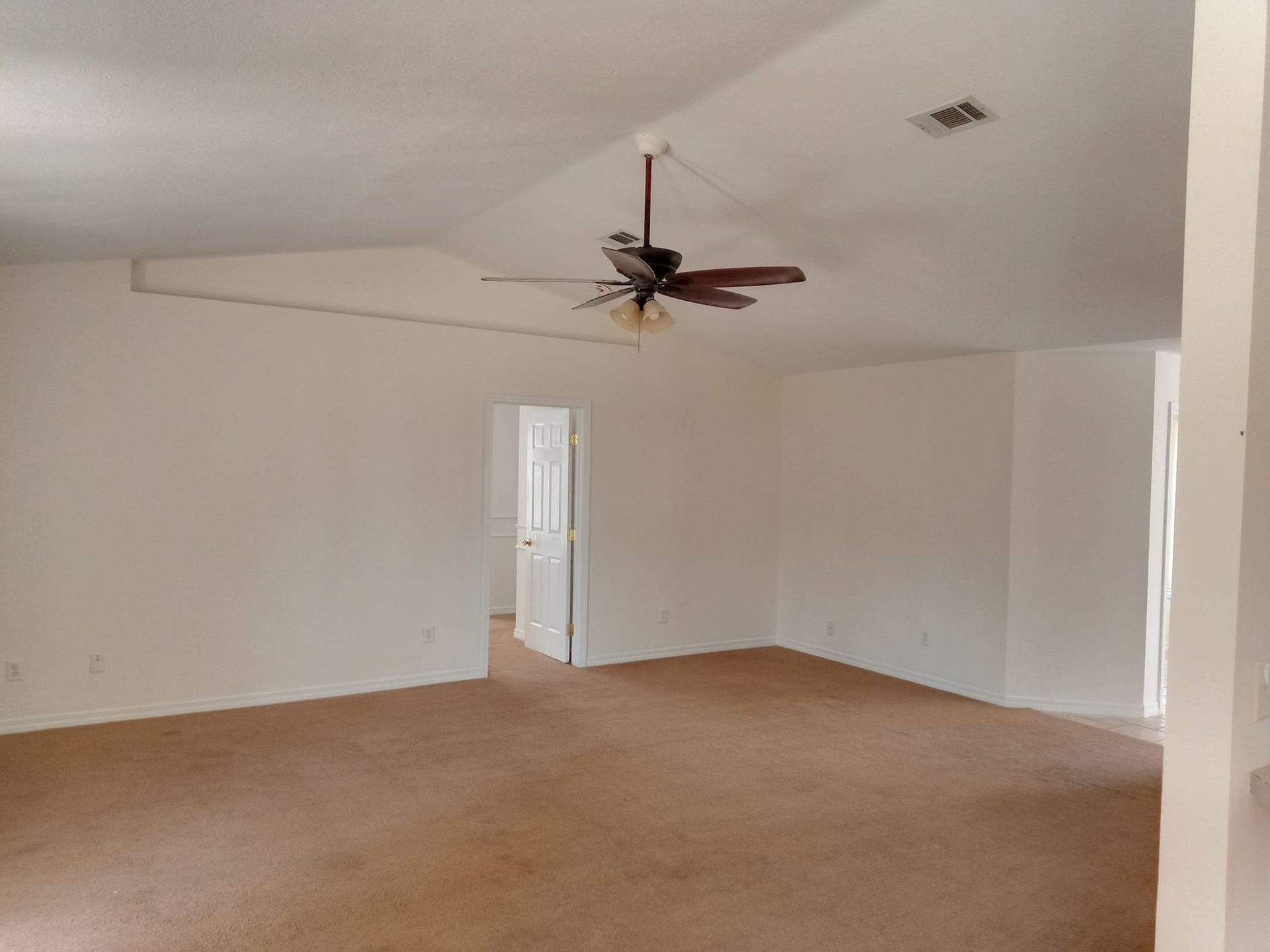 An empty room with a ceiling fan in the corner