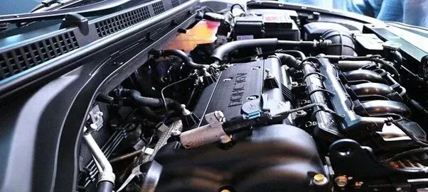 Um close do motor de um carro com o capô aberto.