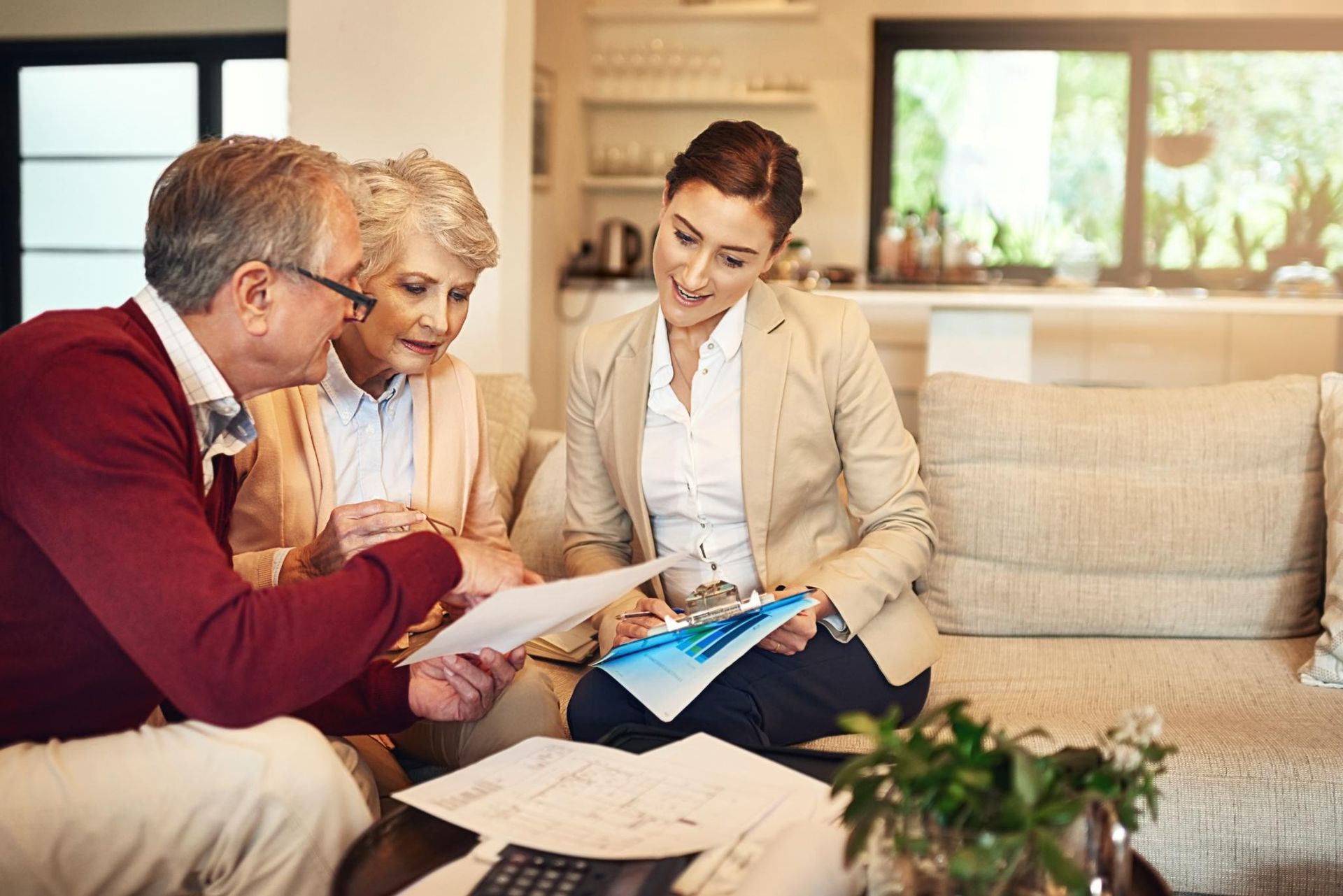 Couple consults with a financial advisor at home, reviewing documents.