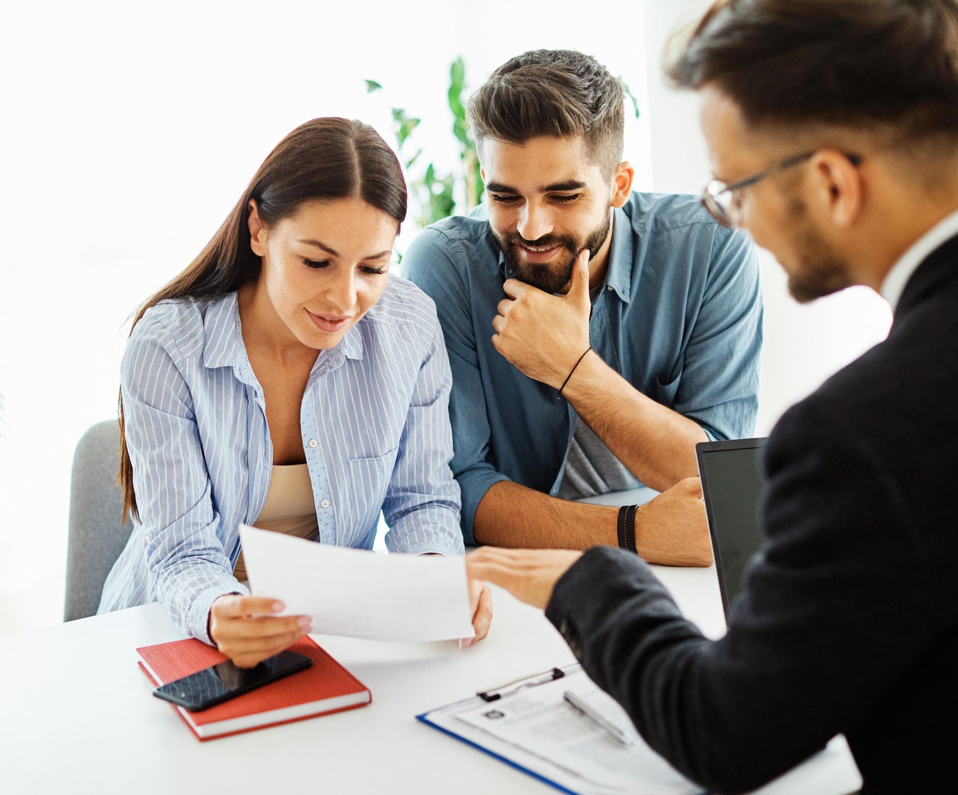Couple reviewing documents with a professional in an office setting.