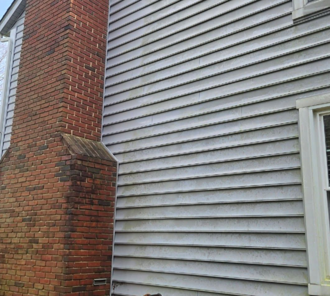 White vinyl siding next to a red brick chimney on a house exterior