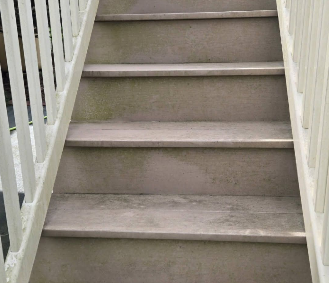 Narrow indoor staircase with light gray steps and white railings on both sides
