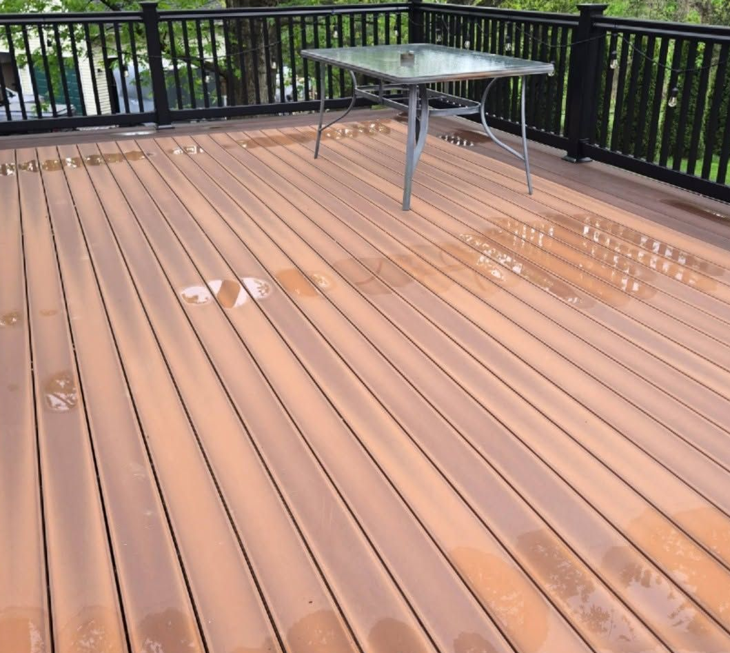 Wet wooden deck with black railing and a glass table near the top center.
