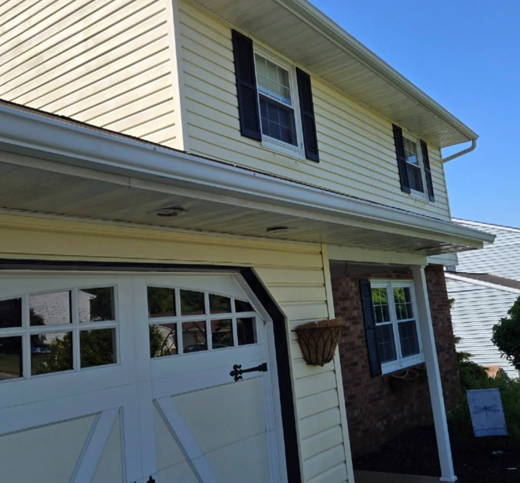 Two-story cream house with garage and front porch in bright sunlight