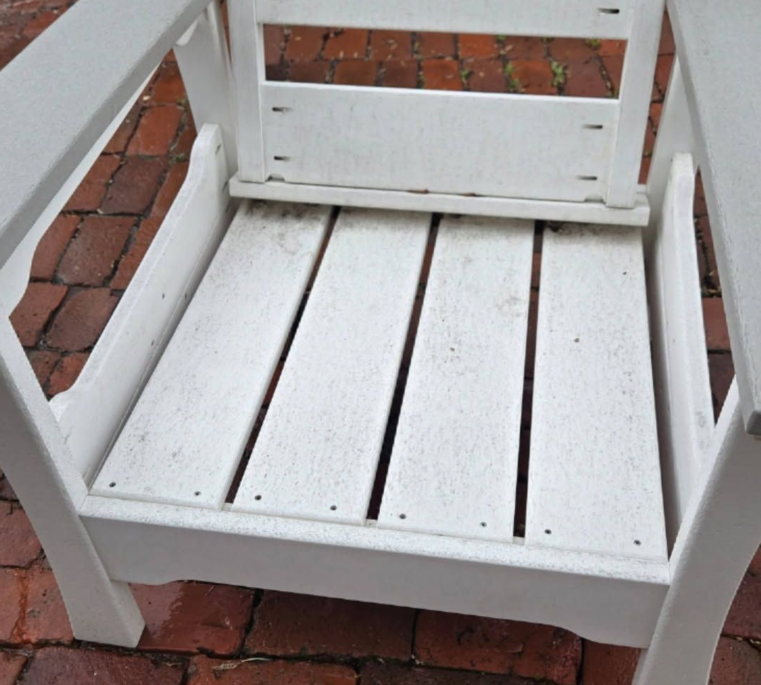 White wooden chair seat on red brick patio, viewed from above