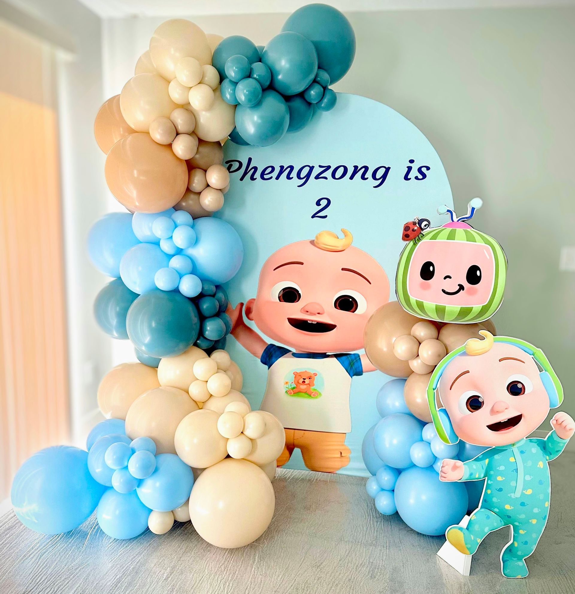 A colorful Cocomelon-themed birthday display with balloons and cartoon characters. It says