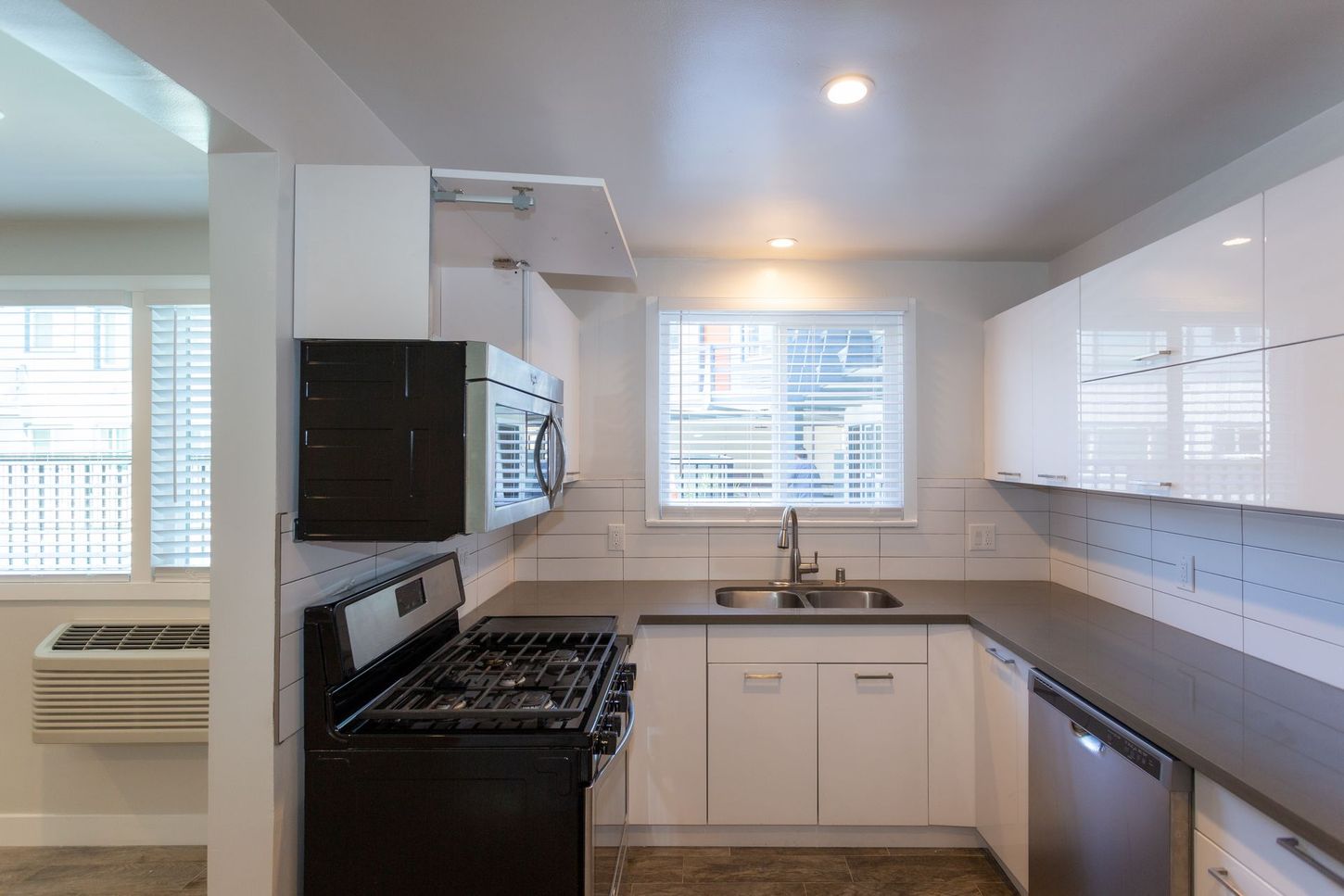 Bright modern kitchen with white cabinets, black stove, and a window over the sink