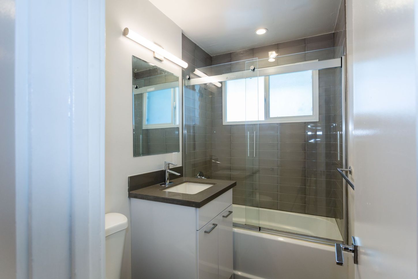 Modern bathroom with glass shower, vanity sink, mirror, and white walls