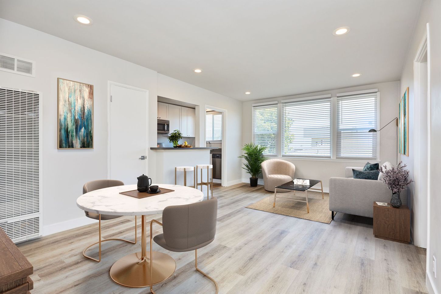 Bright open living room with white walls, gray sofa, round table, and large windows with city view