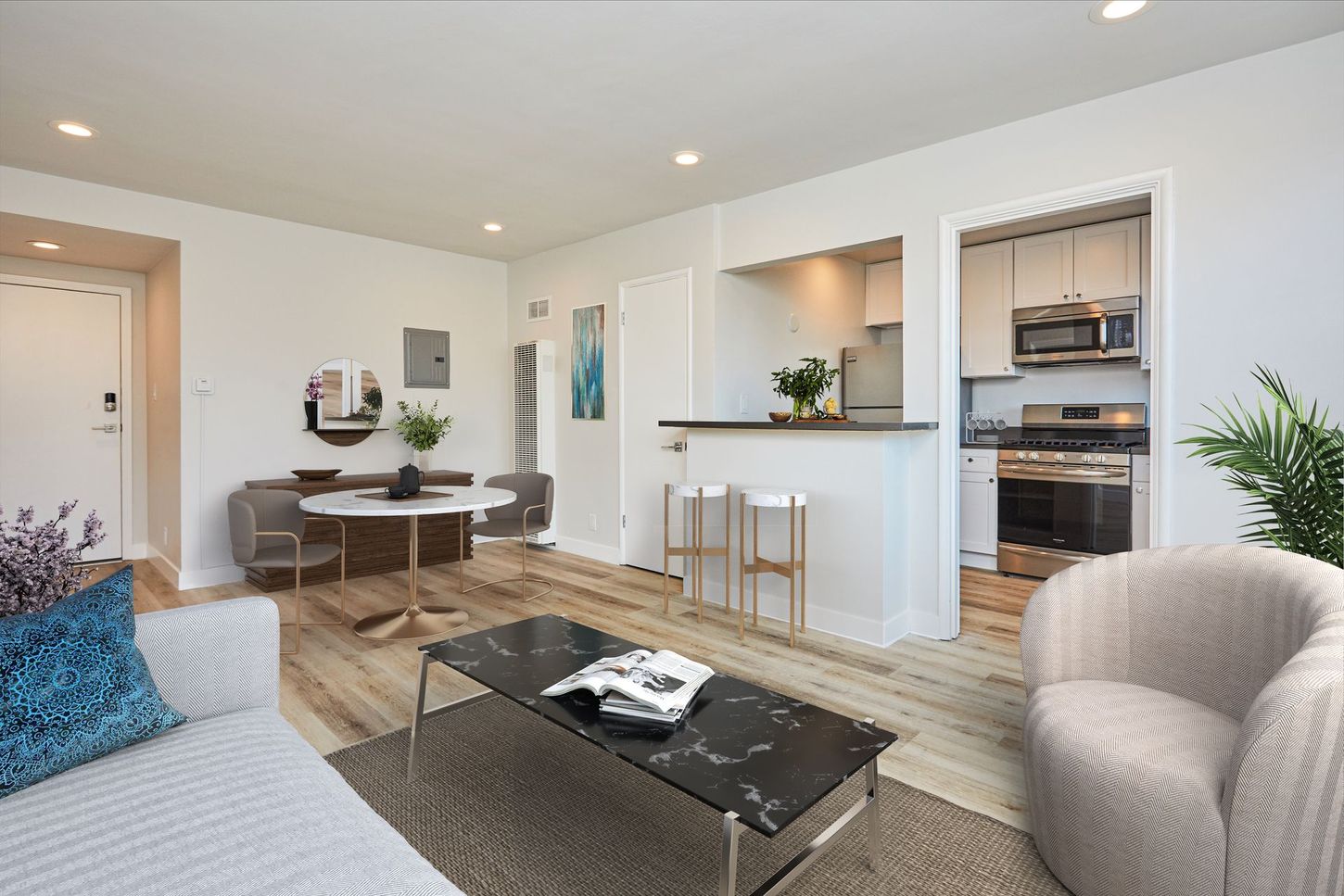 Bright modern living room with dining area, kitchen pass-through, and gray seating