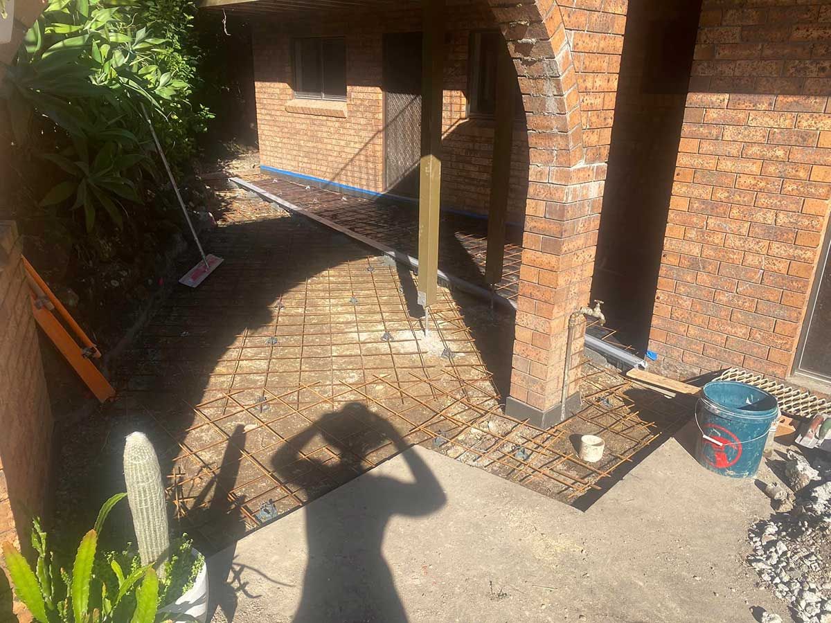 A Person Is Taking a Picture of A Brick Walkway in Front of A Brick Building — Shaka Concreting In South Golden Beach, NSW
