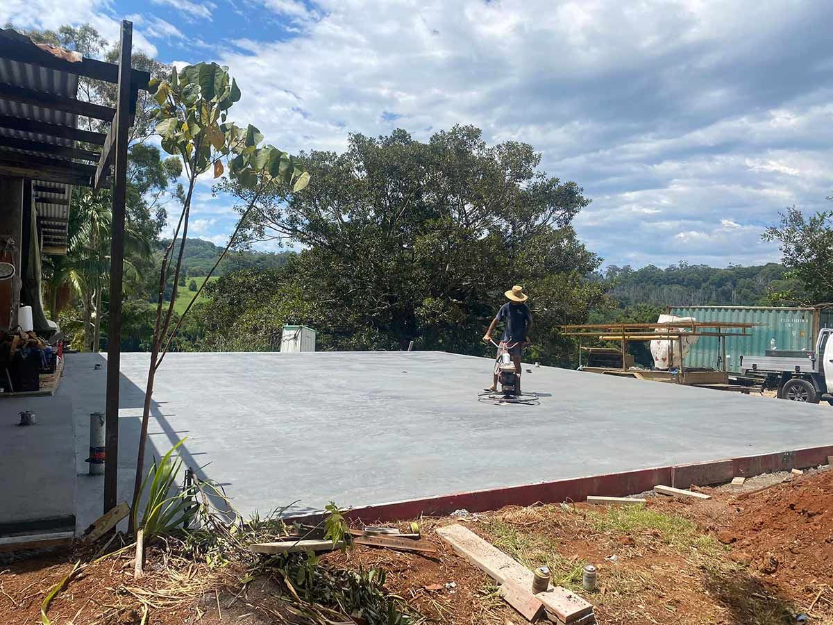 A Man Is Standing on A Concrete Surface in Front of A House — Shaka Concreting In South Golden Beach, NSW