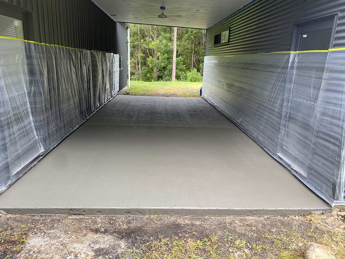 A Concrete Driveway Is Being Painted in Front of A House — Shaka Concreting In South Golden Beach, NSW