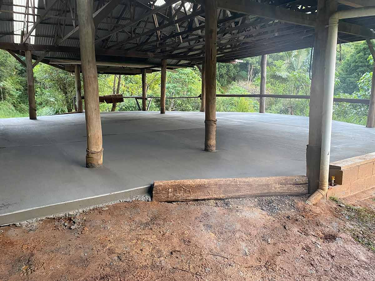 A Large Concrete Floor Under a Wooden Structure with Trees in The Background — Shaka Concreting In Mullumbimby, NSW
