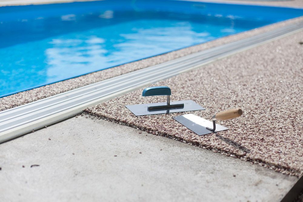 A Trowel Sitting on A Concrete Surface Next to A Swimming Pool — Shaka Concreting In South Golden Beach, NSW
