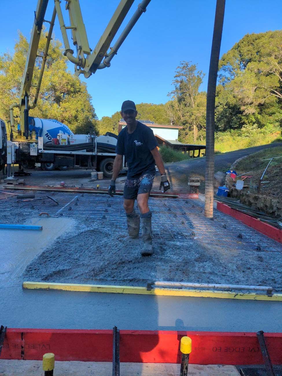 A Man Is Standing in A Pile of Concrete in Front of A Concrete Pump — Shaka Concreting In South Golden Beach, NSW