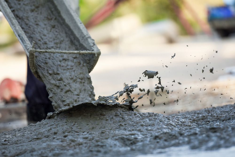 A Person Is Pouring Concrete from A Bucket onto The Ground — Shaka Concreting In South Golden Beach, NSW