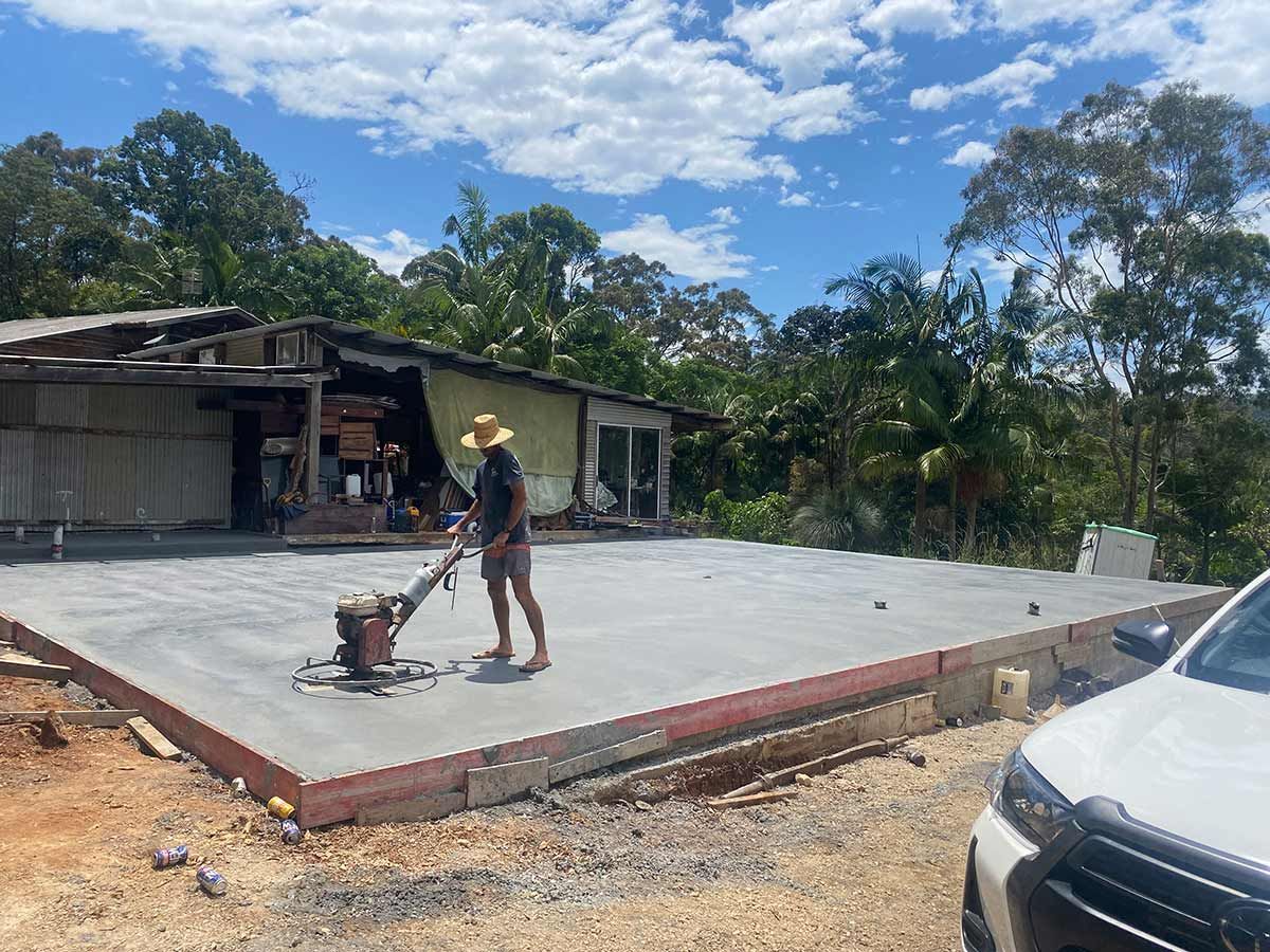 A Man Is Grinding Concrete in Front of A House — Shaka Concreting In South Golden Beach, NSW
