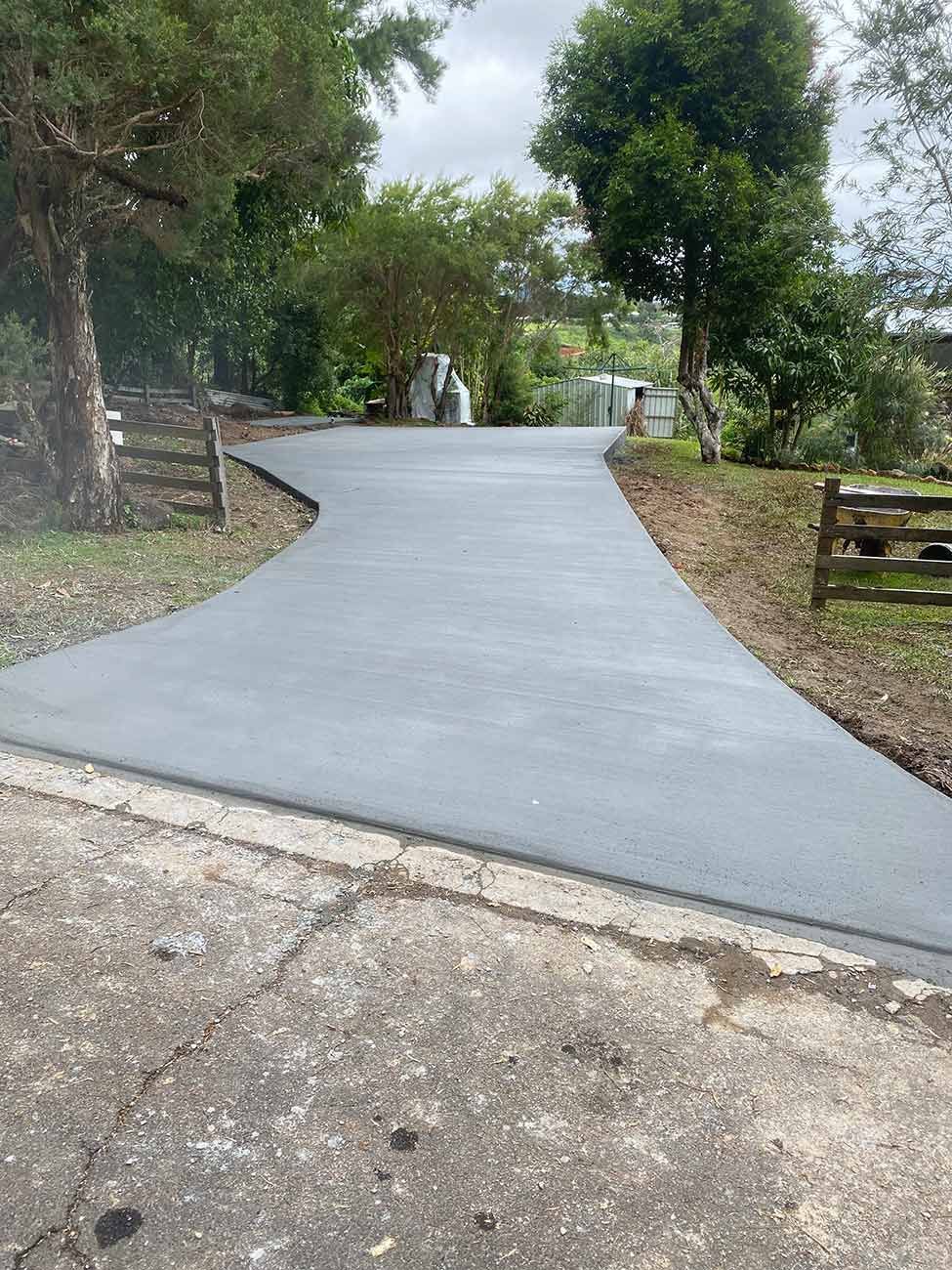 A Man Is Spreading Asphalt on A Road with A Broom — Shaka Concreting In South Golden Beach, NSW