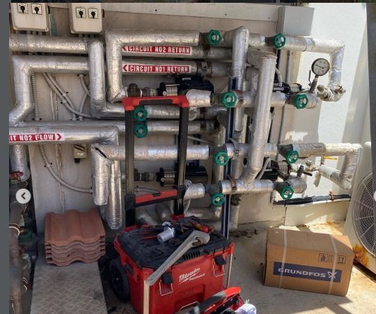 Piping system with valves and gauges, Milwaukee tool cart, and a cardboard box.