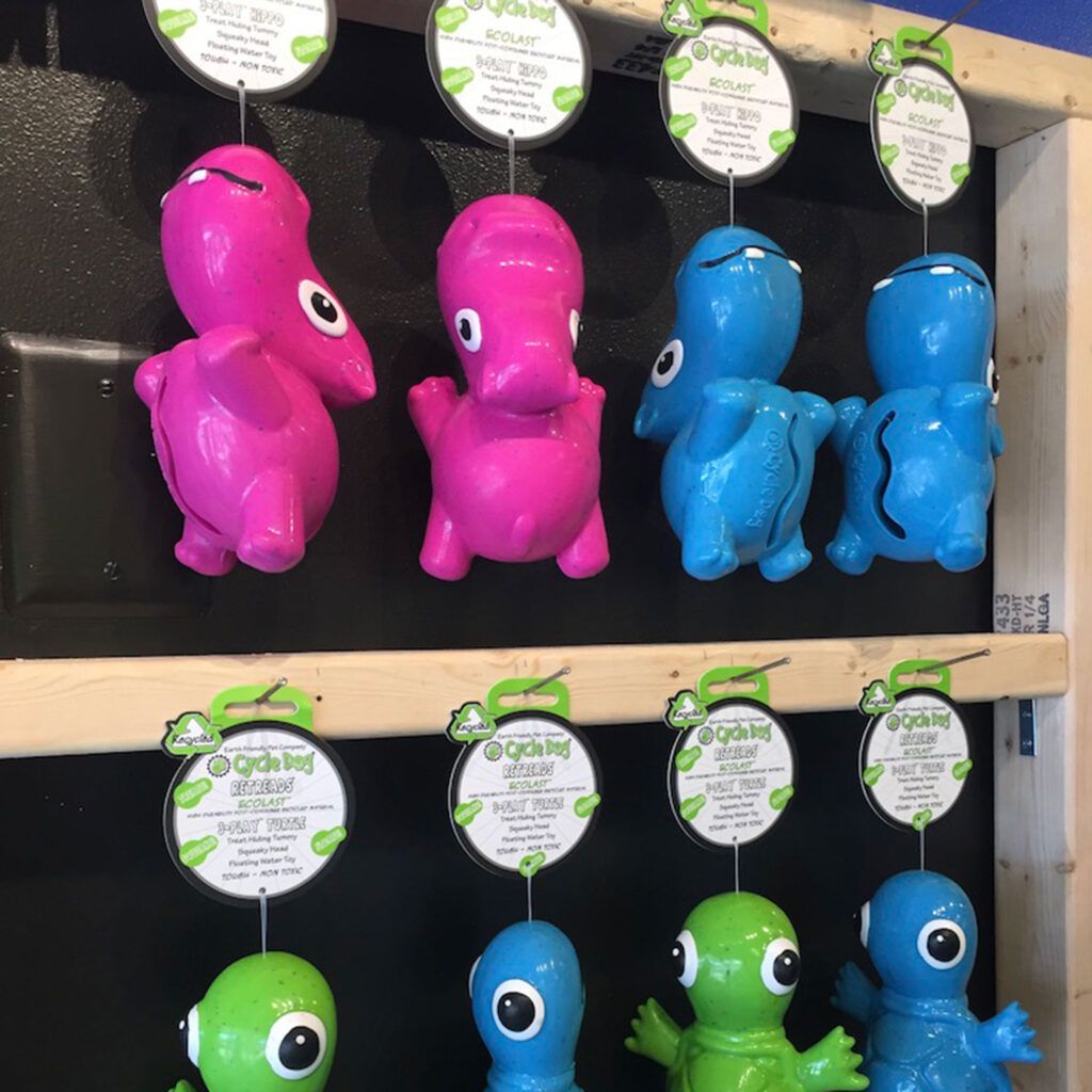 A bunch of toy dinosaurs are hanging on a shelf