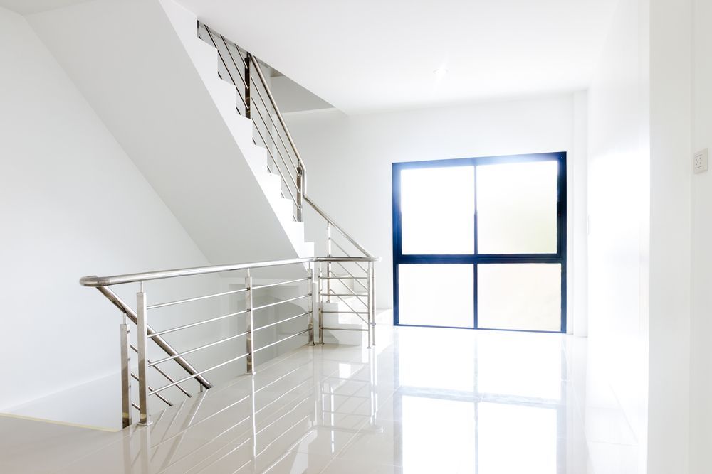 Empty White Staircase with Stainless Steel Handrails, and A Large Window — SS Building Services in Townsville, QLD