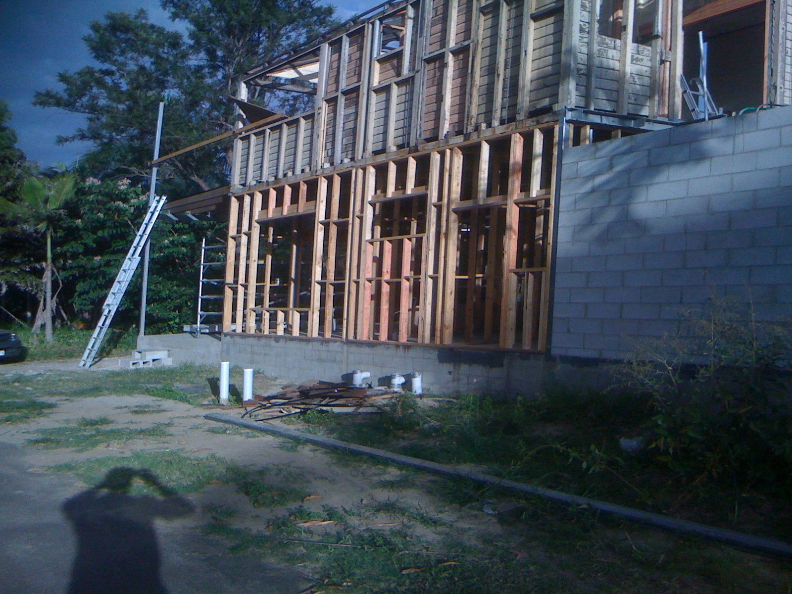 Partially Built Wooden House Frame Beside a Gray Cinderblock Wall — SS Building Services in Townsville, QLD