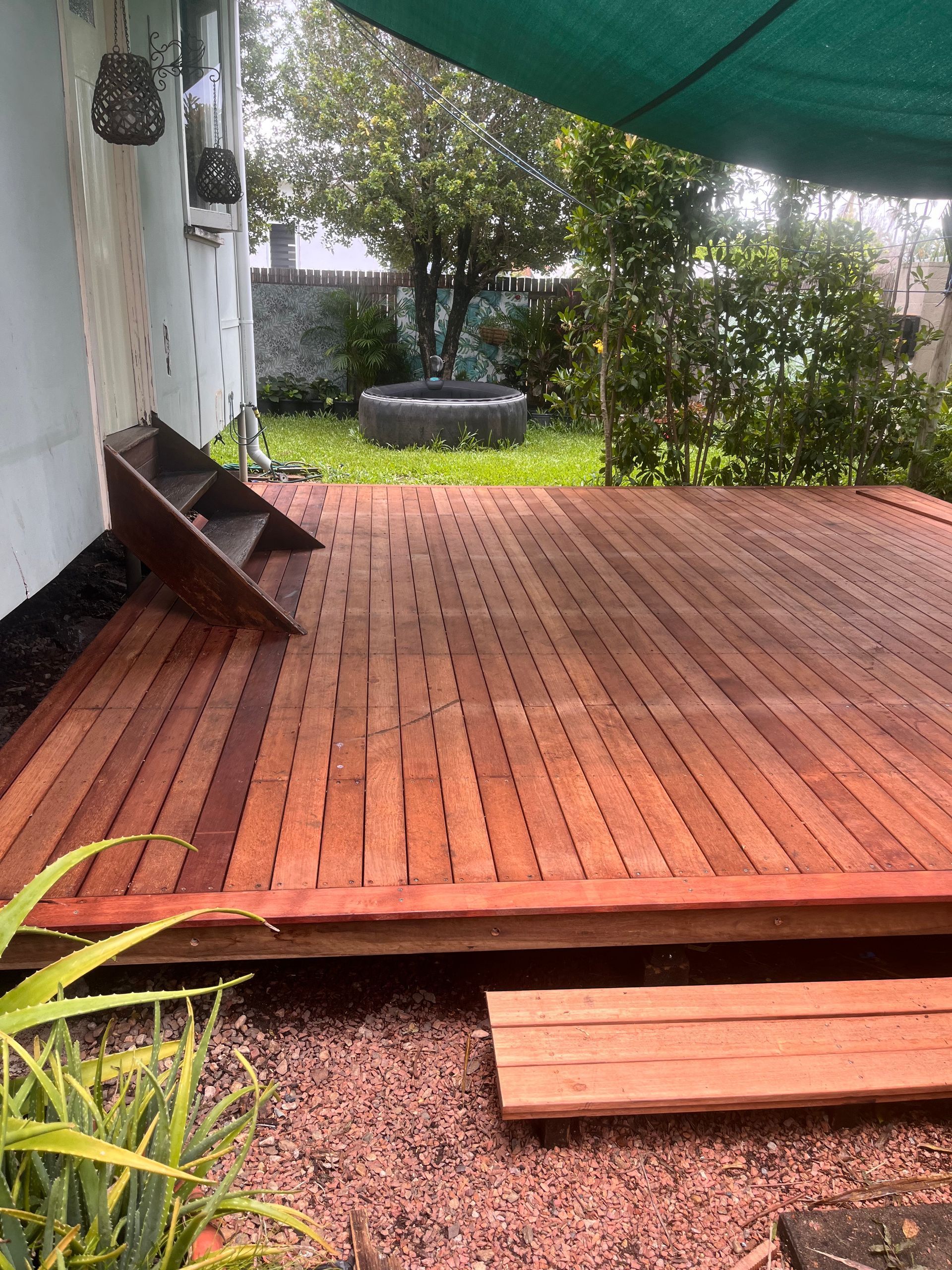 Wooden Deck and Steps Beside a House, with A Garden and Brick Path Beyond — SS Building Services in Townsville, QLD