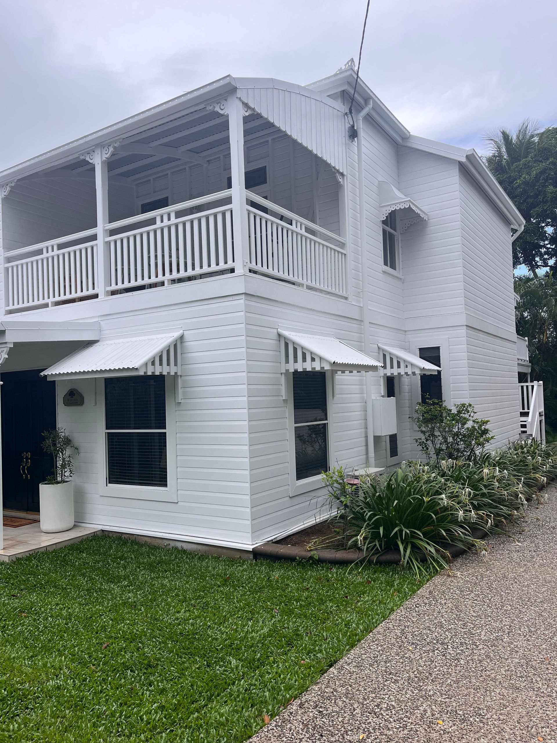 White Two-Story House with Wraparound Balcony, Awnings, and A Green Lawn — SS Building Services in Townsville, QLD