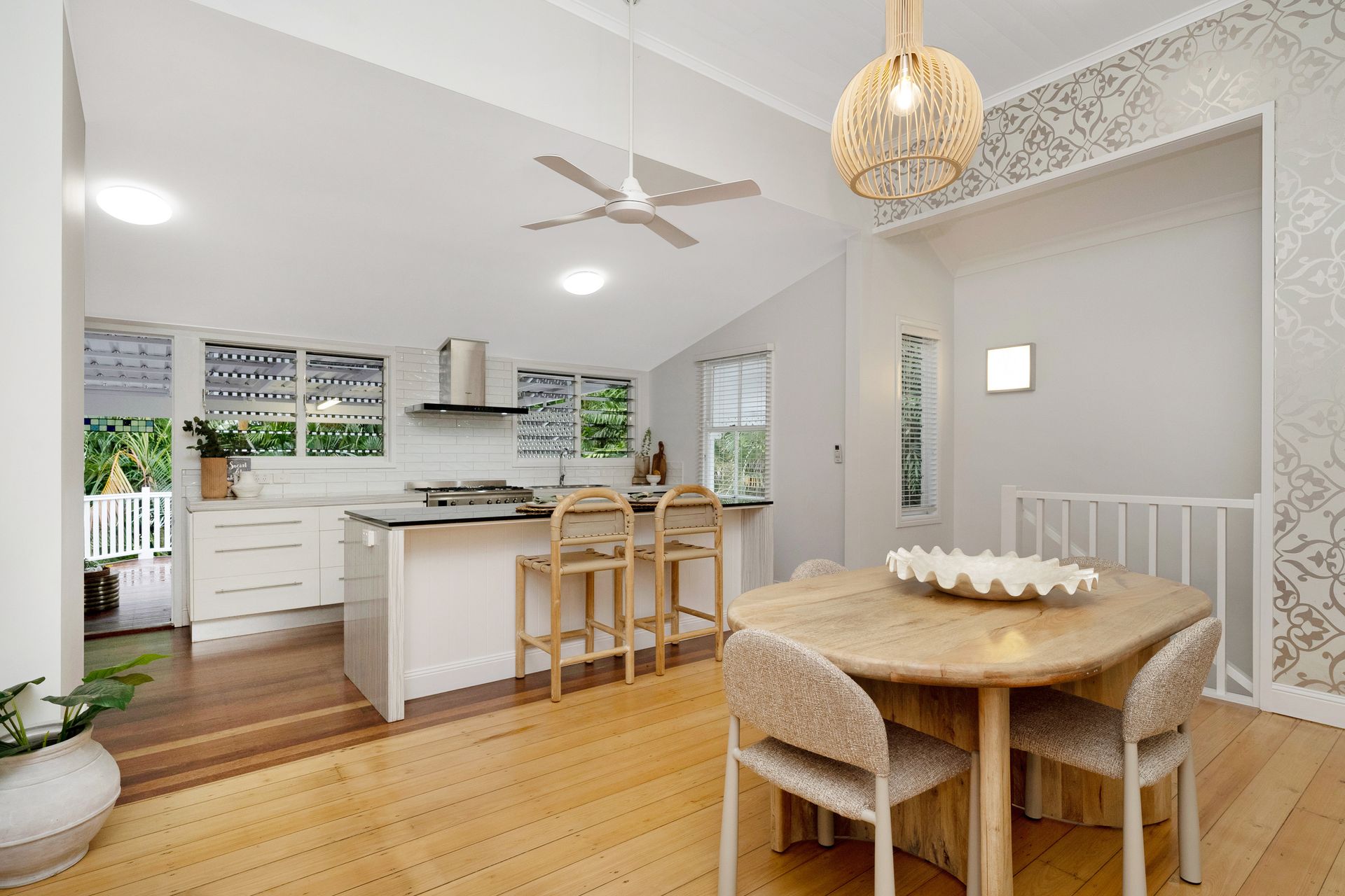 Bright Open Kitchen and Dining Area with White Cabinets and Wood Floors — SS Building Services in Townsville, QLD