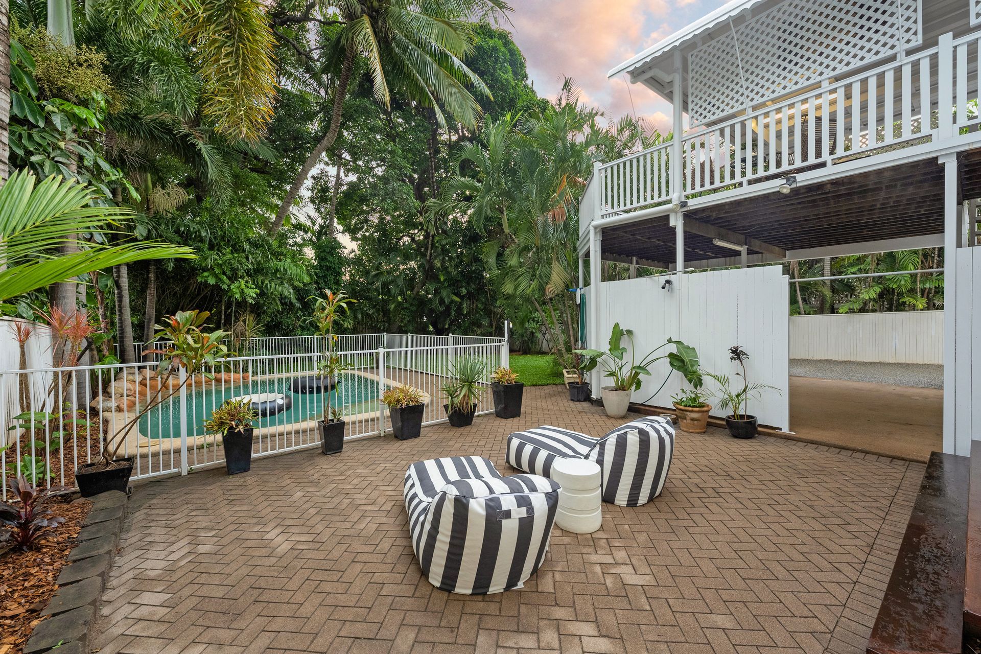 Outdoor Patio with Striped Beanbags, Potted Plants, and A White Railing at Sunset — SS Building Services in Townsville, QLD