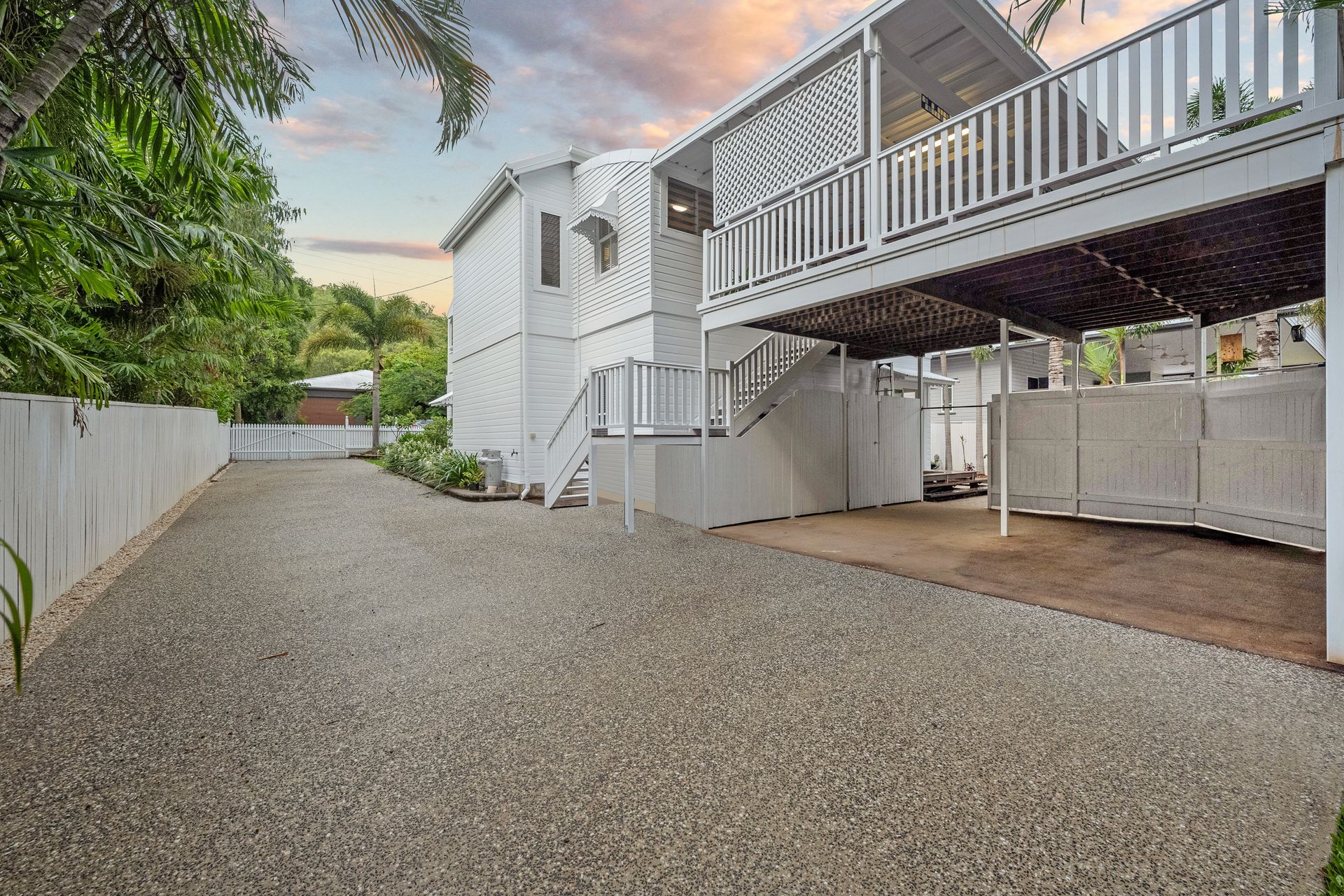 Gravel Driveway Beside a White House with An Elevated Deck and Stairs at Sunset — SS Building Services in Townsville, QLD